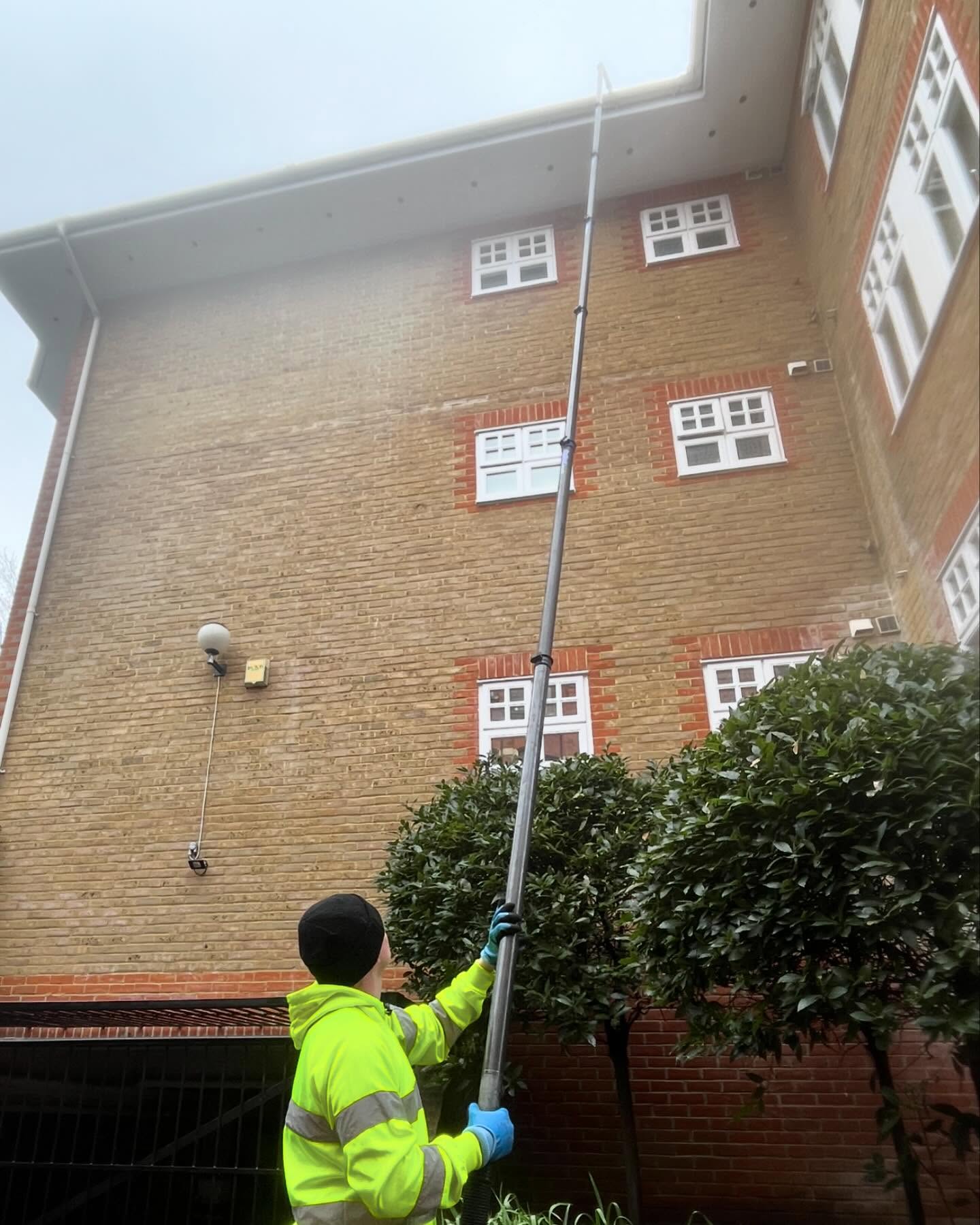 A man cleaning gutters on a high building